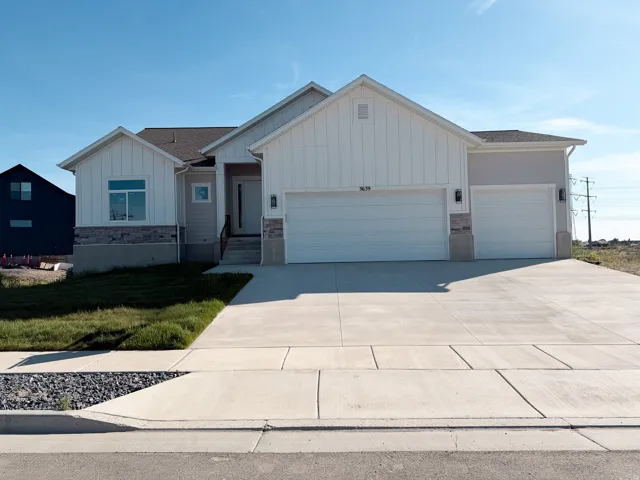 Modern farmhouse exterior featuring board and batten siding, stone veneer accents, a three-car garage, and a concrete driveway