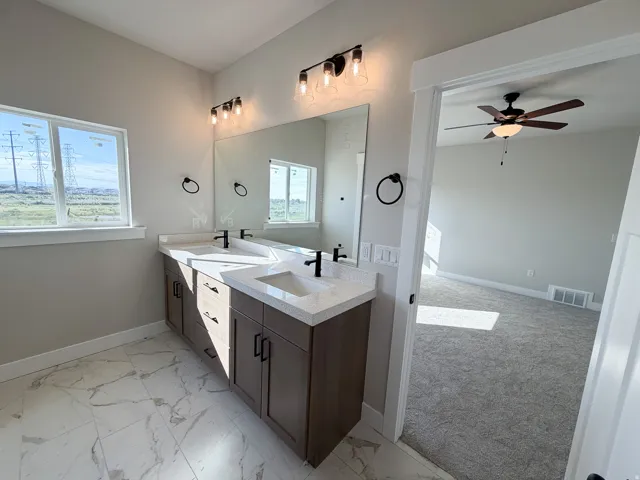 Bathroom featuring a dual vanity with quartz countertops, undermount sinks, and matte black fixtures
