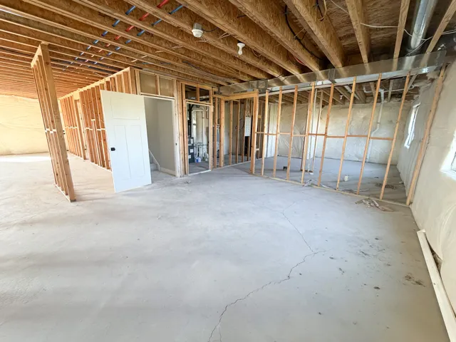 Unfinished lower level with concrete flooring, exposed wood joists, and framed interior walls, offering customization potential