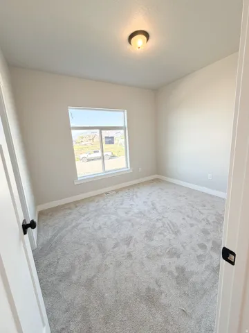 Neutral-toned room with light gray carpet, white baseboards, and a single window