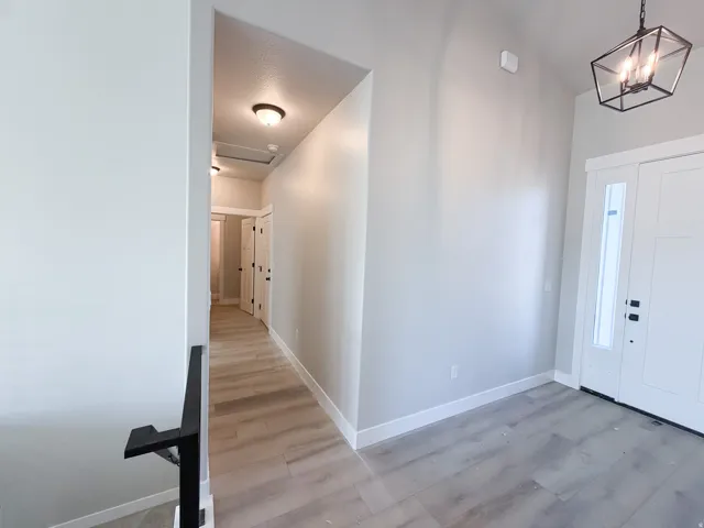 Entryway featuring wood-finish flooring, a contemporary pendant light fixture, and a white paneled door with an integrated glass panel