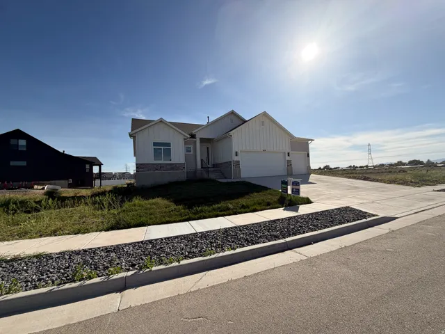 Contemporary exterior featuring vertical siding, stone accents, and a dual garage door