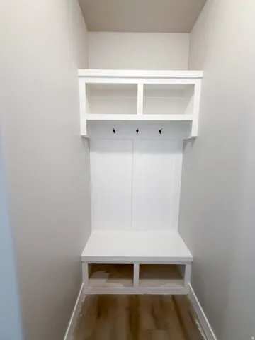 Built-in mudroom bench with white cabinetry, open shelving, and integrated coat hooks
