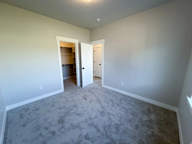 Neutral-toned room featuring plush grey carpeting and crisp white baseboards