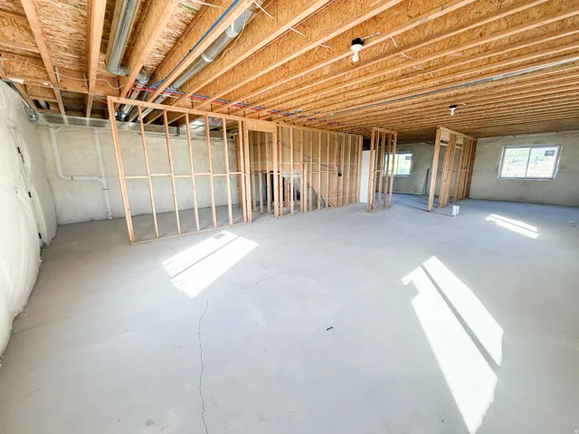 Unfinished basement featuring wood framing for future rooms, exposed ceiling joists, and concrete flooring