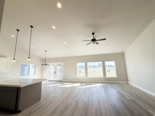 Open-concept living area featuring vaulted ceilings, recessed lighting, and wood-finish flooring