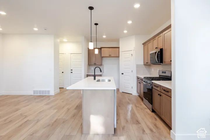 Kitchen featuring wood-finish flooring, recessed lighting, and an island with a sink and pendant lights