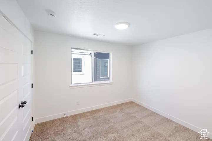 White painted walls, neutral carpet, and a window for natural light