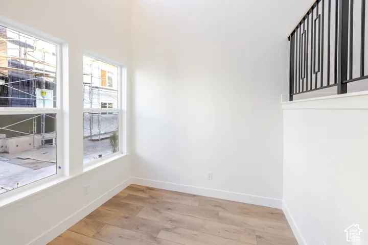 Wood-finish flooring, white trim, and a black wrought iron railing