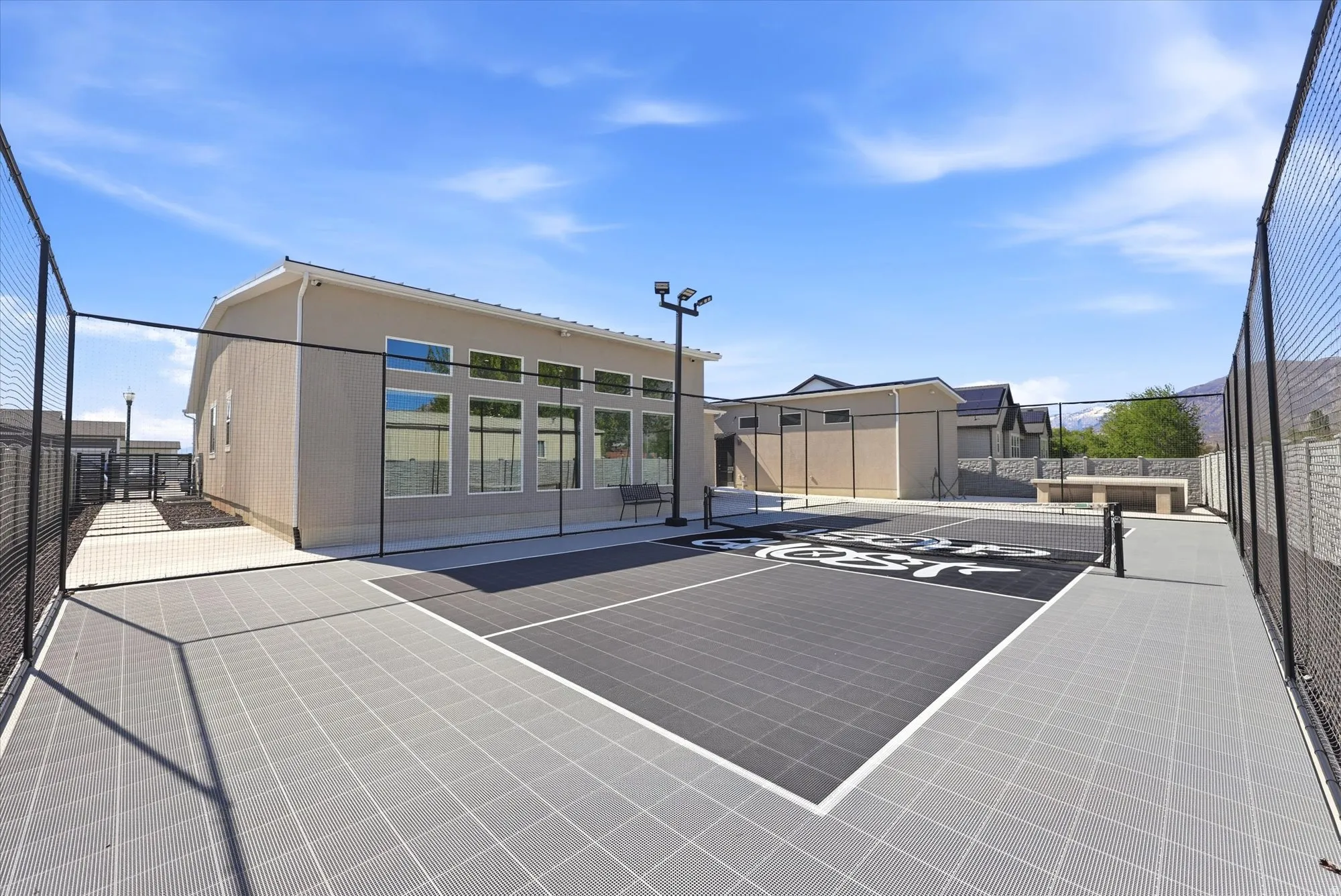 Outdoor sports court featuring a durable grid surface, perimeter fencing, and built-in lighting