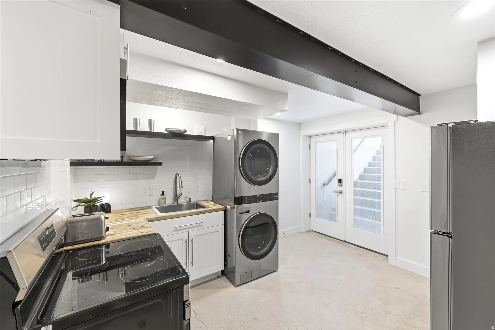 Compact kitchen area featuring a wood-finish countertop, white subway tile backsplash, and stainless steel sink
