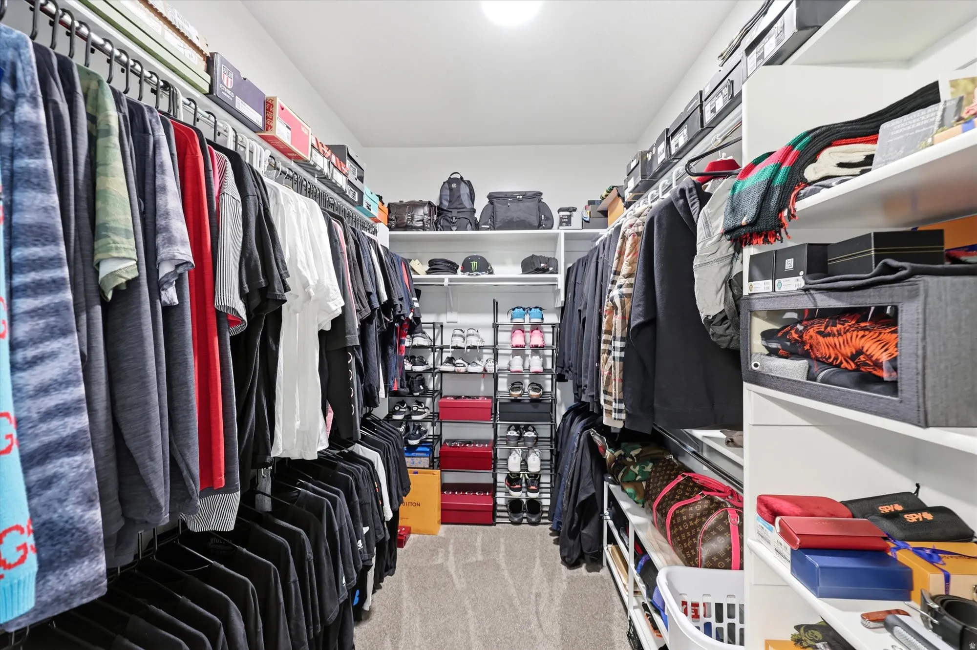 Expansive walk-in closet featuring extensive built-in shelving, multiple hanging rods, and integrated overhead lighting