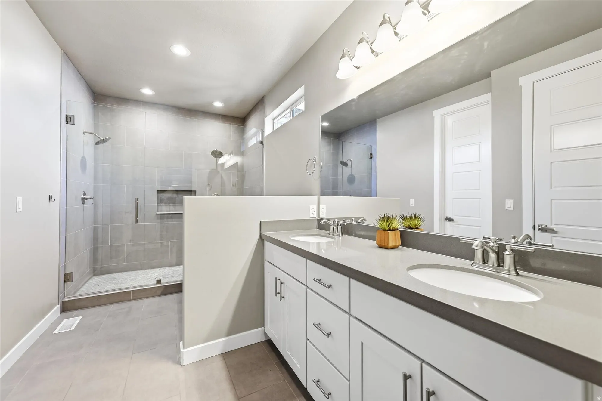 Expansive bathroom featuring a dual vanity with undermount sinks, a substantial mirror, and brushed nickel fixtures