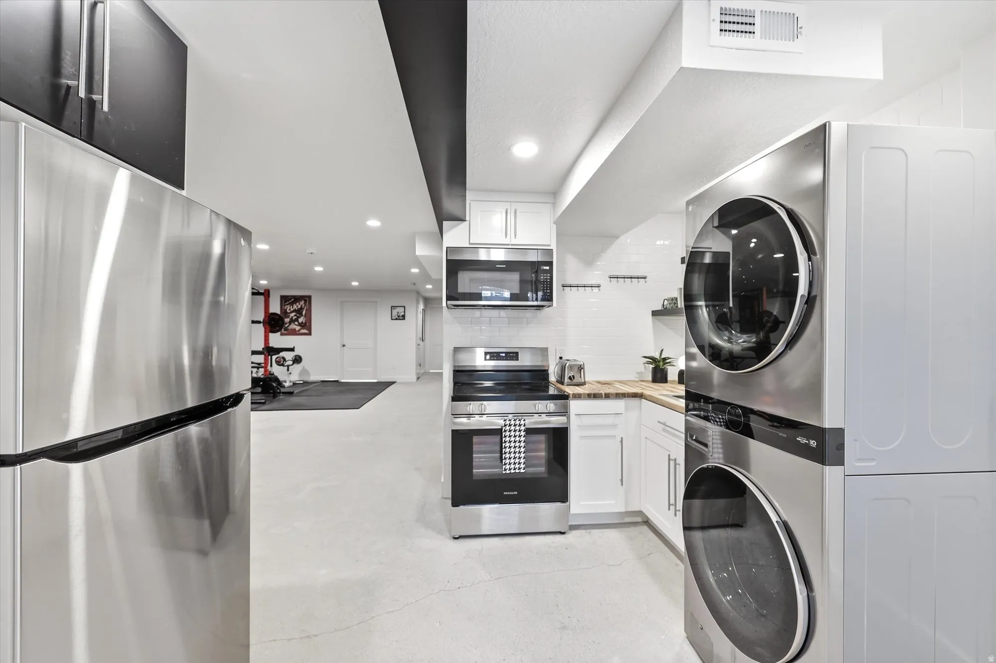 Full kitchen featuring stainless steel appliances, white cabinetry, a wood-finish countertop, and white subway tile backsplash