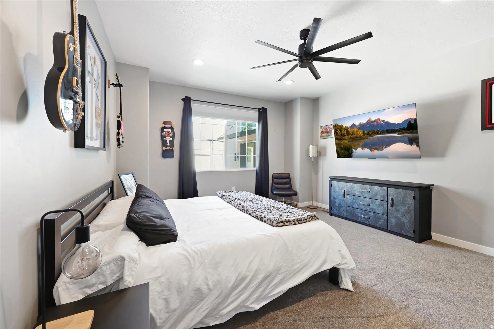 Spacious bedroom featuring light gray painted walls and gray carpet flooring