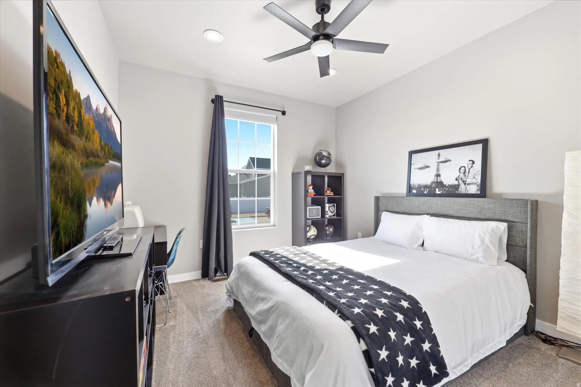 Carpeted bedroom featuring a window with dark drapery, a ceiling fan with integrated lighting, recessed lighting, and a built-in bookshelf