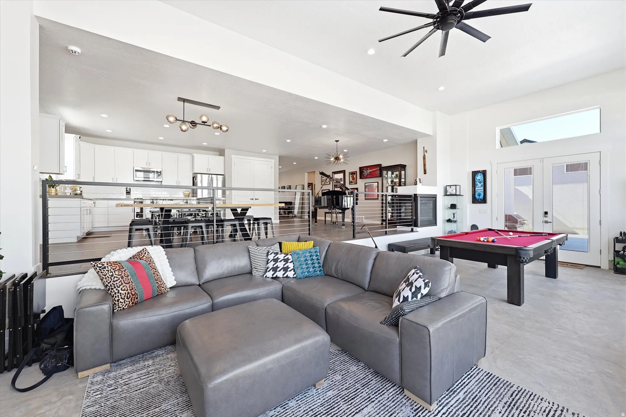 Spacious open-concept living area featuring high ceilings, a large ceiling fan, and concrete flooring