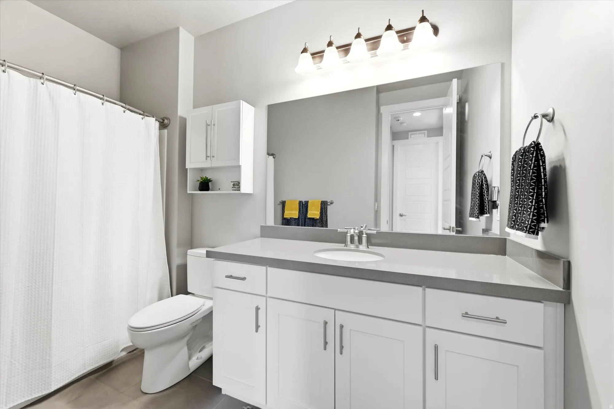 Spacious bathroom featuring a white vanity with extensive counter space, an integrated sink, and an expansive wall-mounted mirror