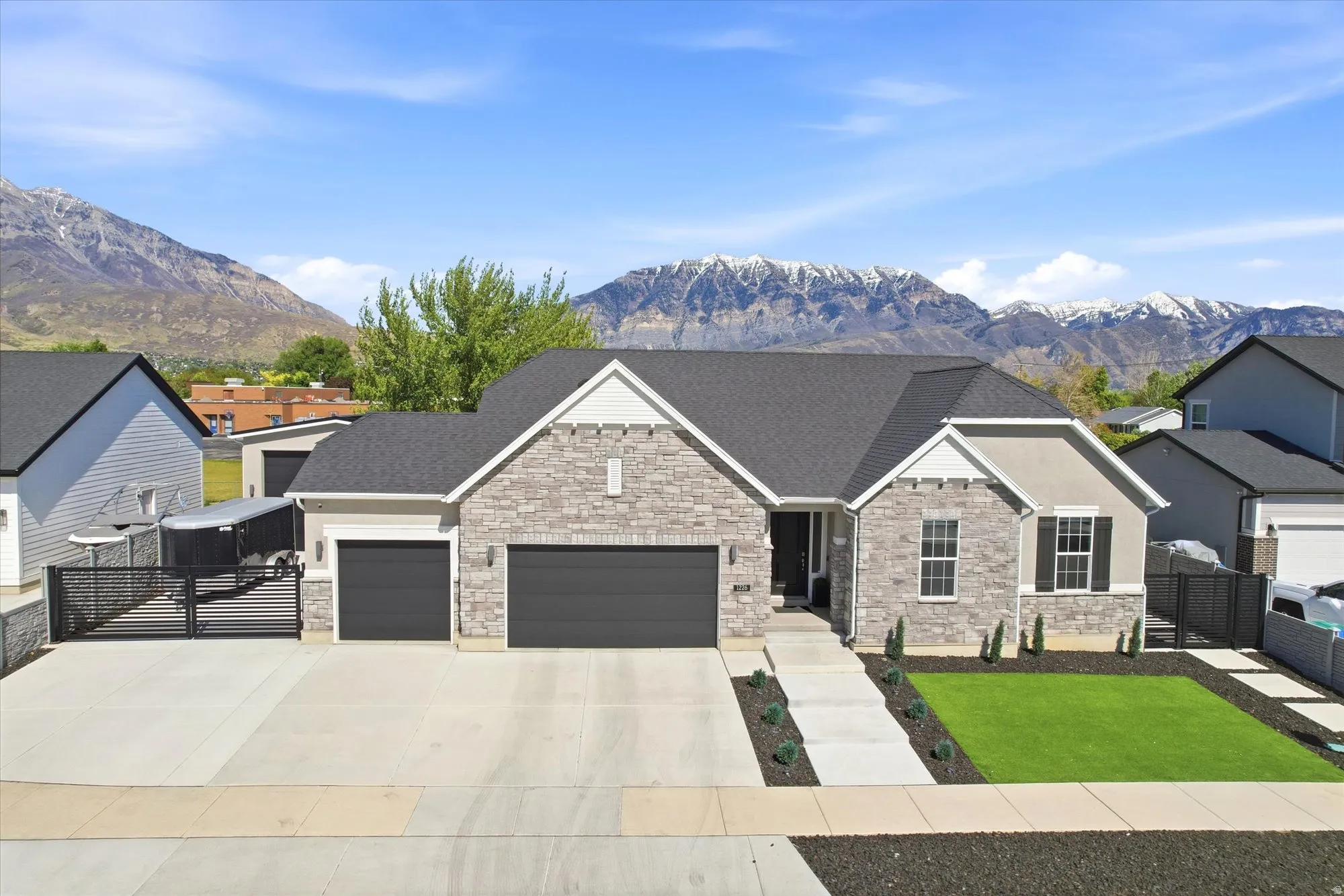 Contemporary home featuring a stone and stucco exterior, dark asphalt shingle roof, two-car garage, and a concrete driveway