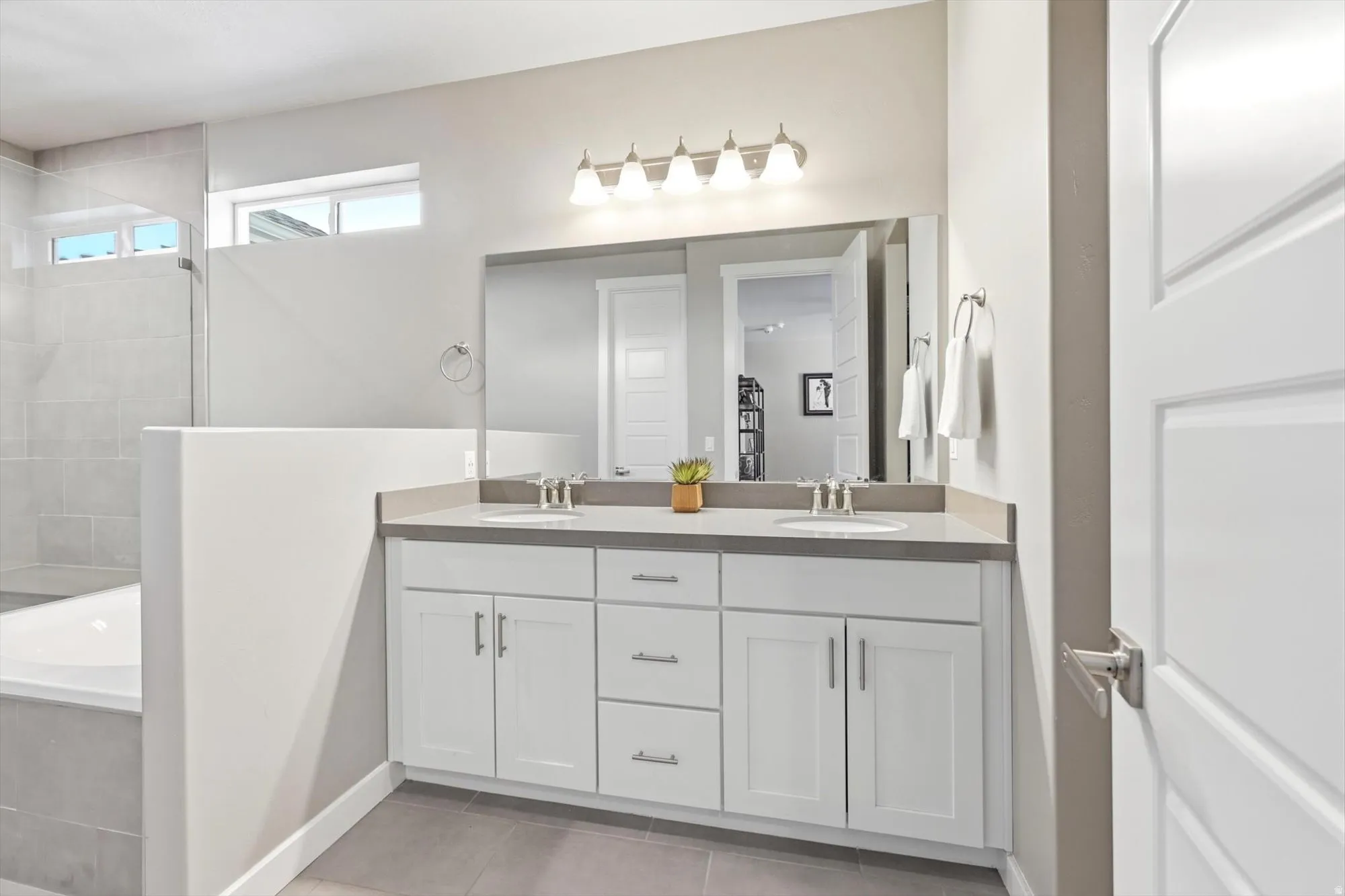 Bathroom featuring a double vanity with white cabinetry, dual undermount sinks, and a stone countertop