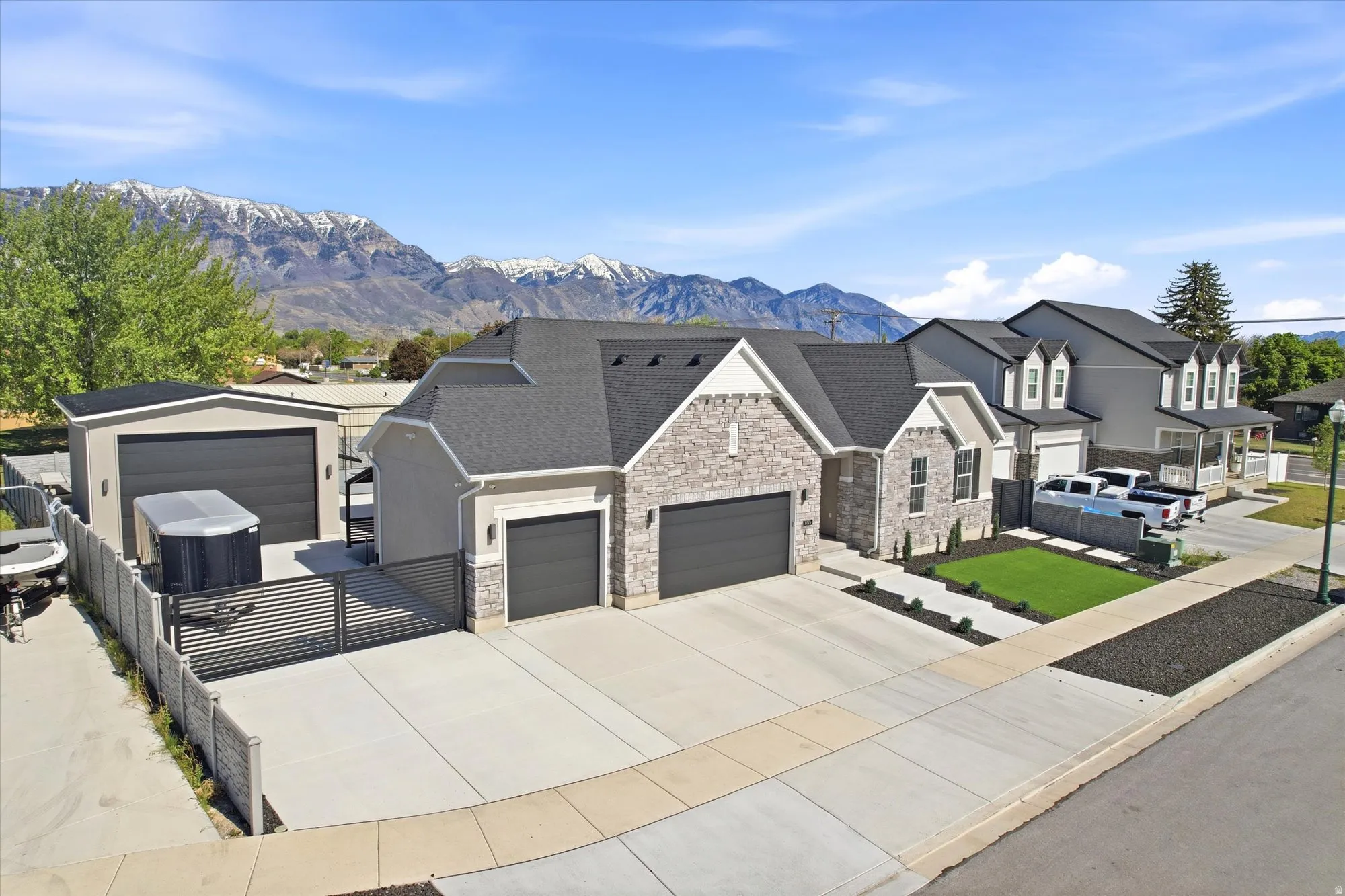 Contemporary home featuring stone and siding exterior, a two-car garage, and a separate detached garage with an automatic gate