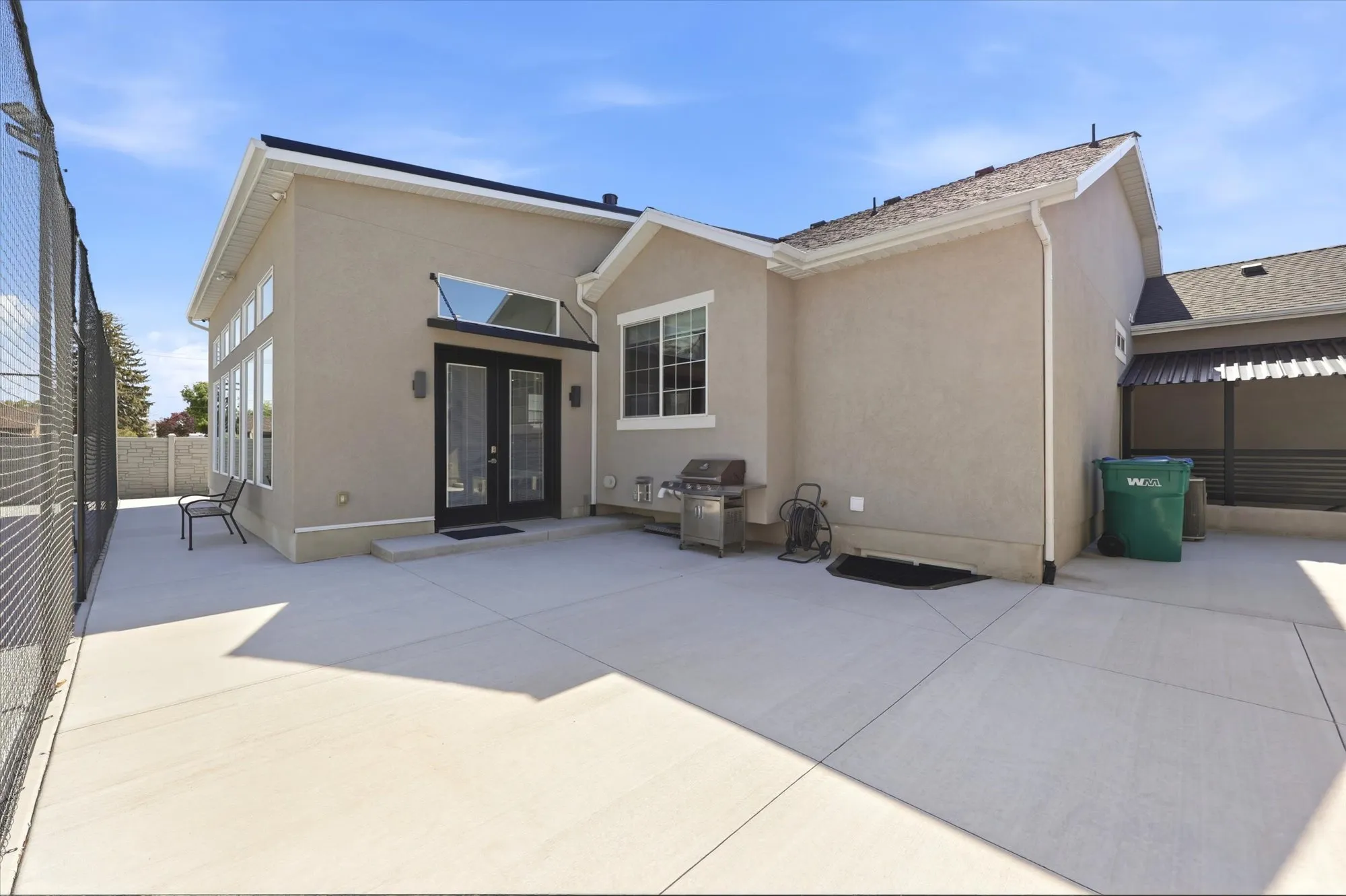 Spacious concrete patio with stucco exterior and black framed double doors