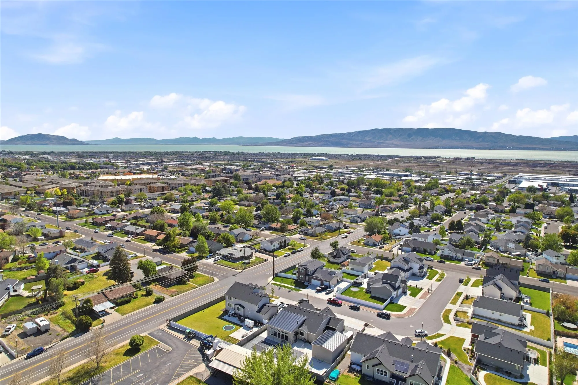 Expansive aerial perspective showcasing a residential neighborhood with a distant body of water and mountain range under a clear sky
