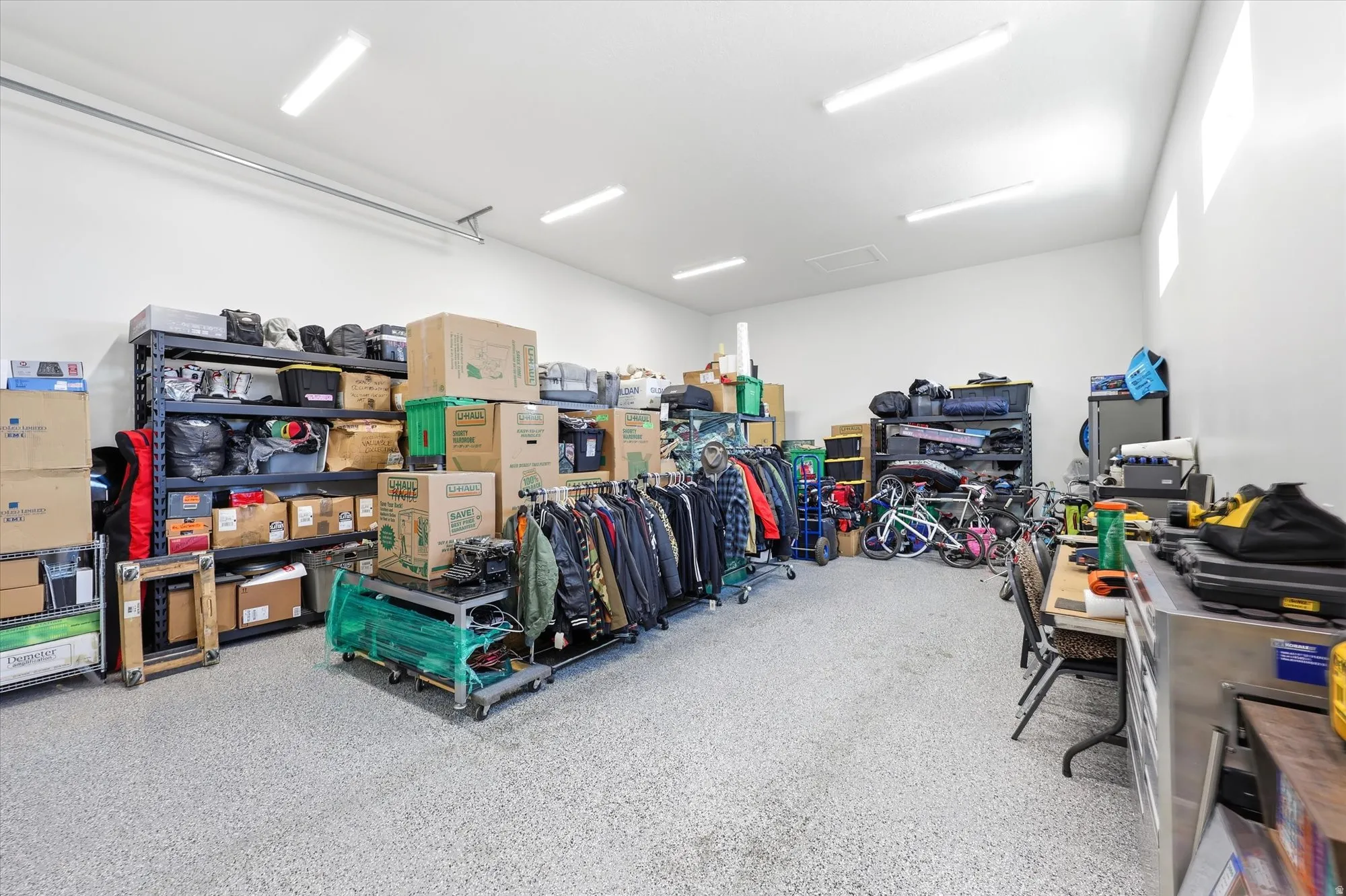 Spacious garage featuring a durable epoxy-coated floor, multiple fluorescent light fixtures, and high ceilings