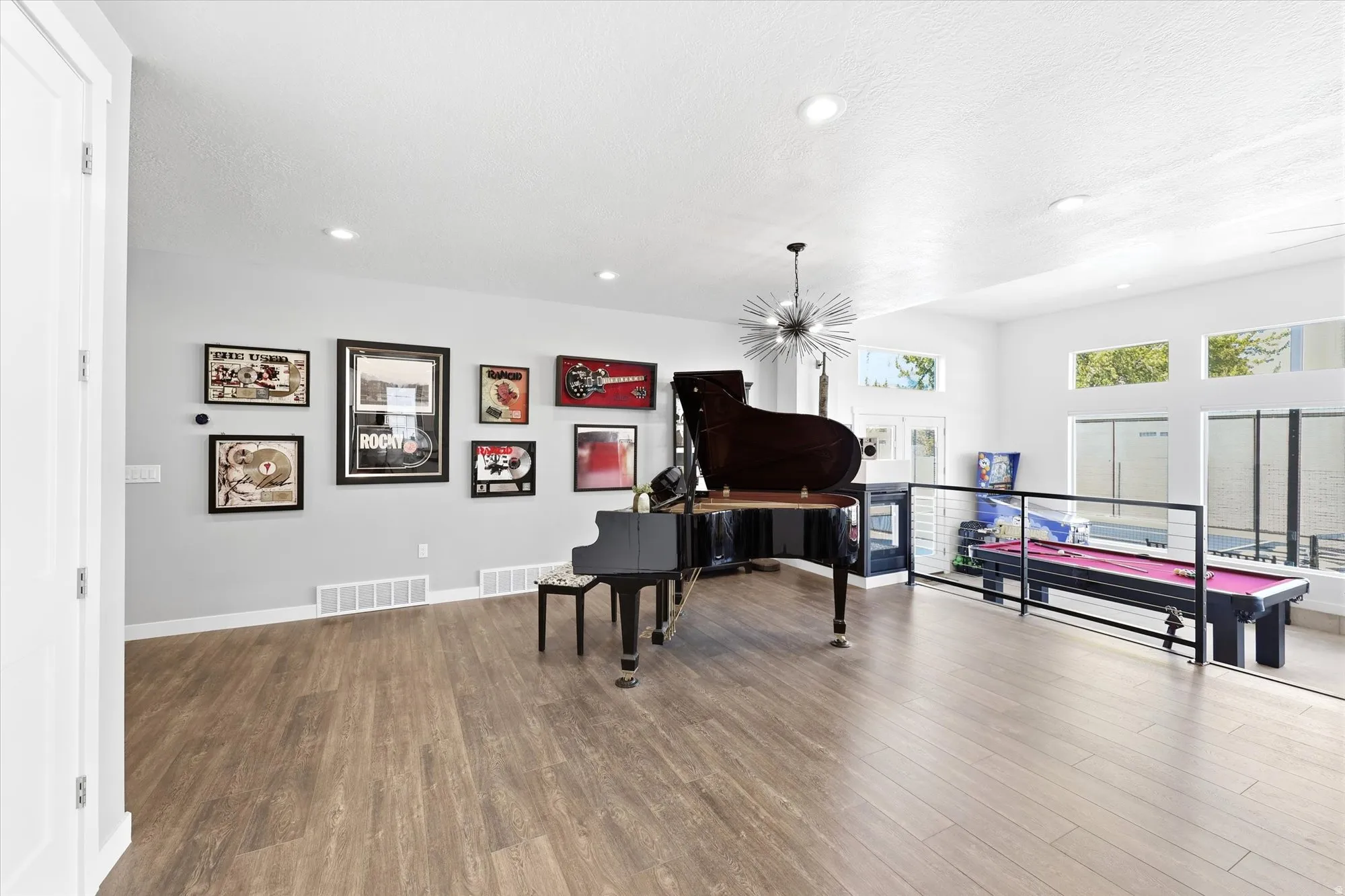 Spacious room featuring wood-finish flooring, recessed lighting, and a modern sputnik chandelier
