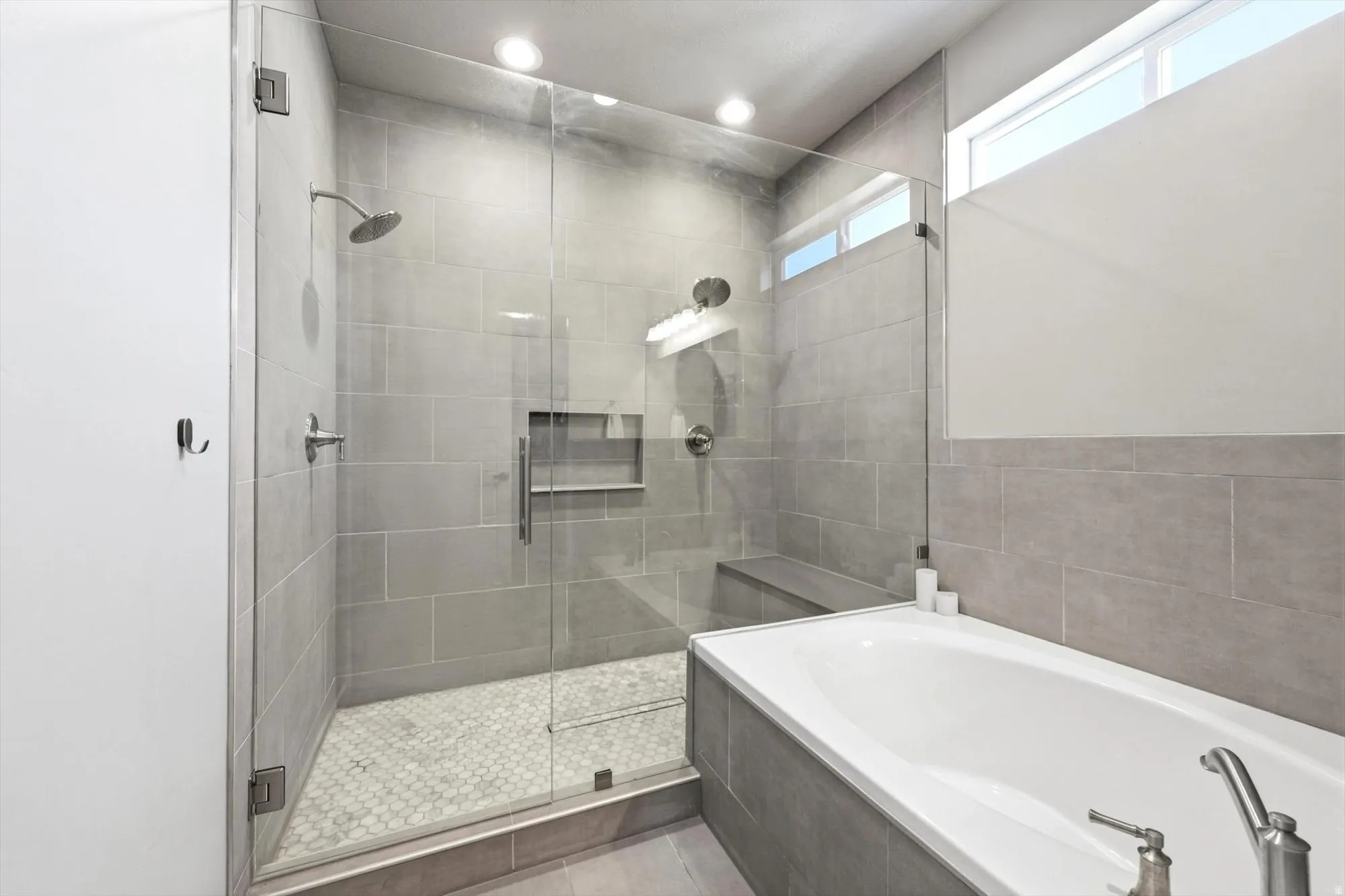Walk-in shower with a glass enclosure, rainfall showerhead, and tile bench seat