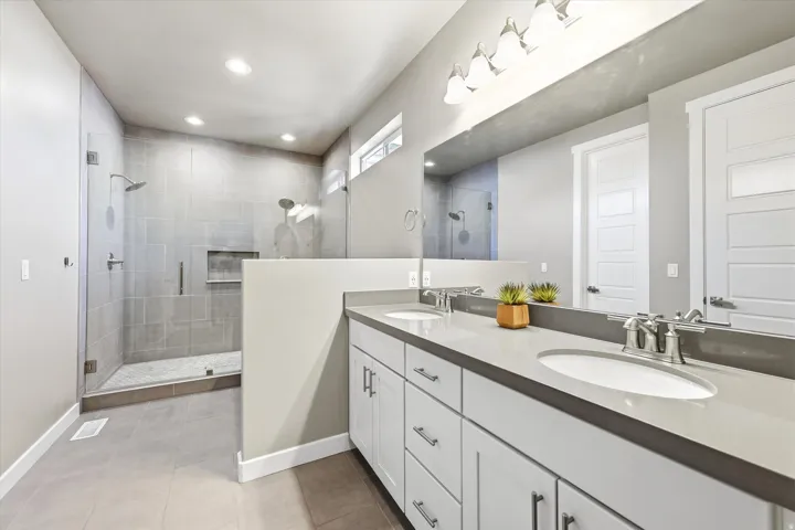 Expansive bathroom featuring a dual vanity with undermount sinks, a substantial mirror, and brushed nickel fixtures