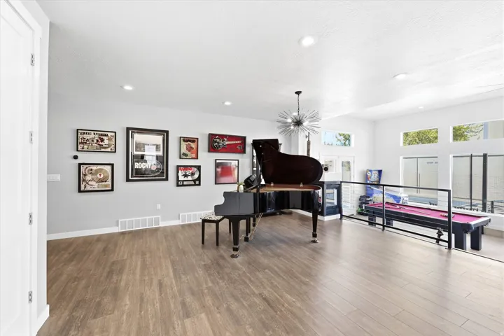 Spacious room featuring wood-finish flooring, recessed lighting, and a modern sputnik chandelier