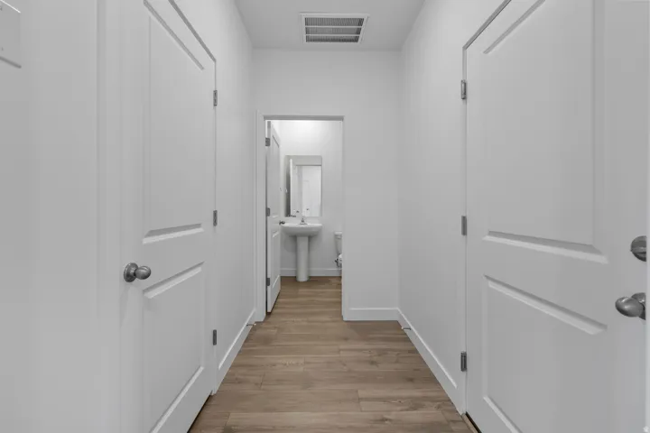 Hallway featuring wood-finish flooring and three white panel doors