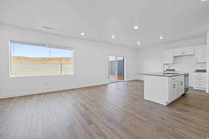 Open-concept living space featuring wood-finish flooring, recessed lighting, and a sliding glass door to an outdoor area