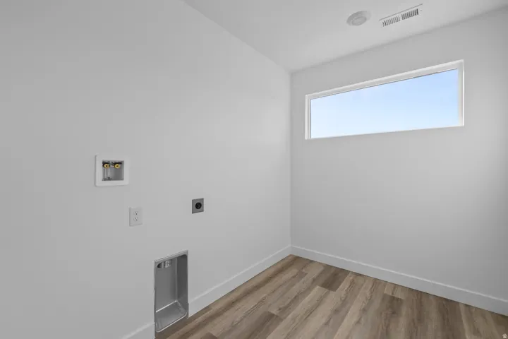 Dedicated laundry space with wood-finish flooring, a contemporary horizontal window, and white baseboards