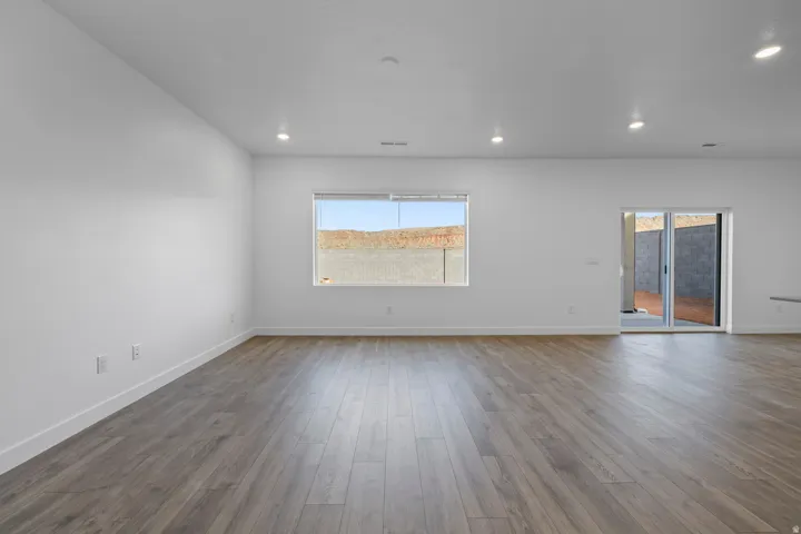 Open concept living area featuring wood-finish flooring, recessed lighting, a large picture window, and direct access to an outdoor patio through sliding glass doors