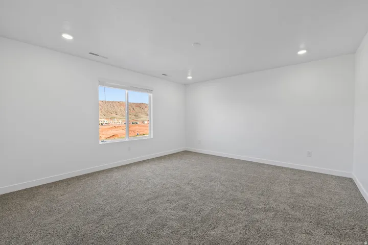 Expansive room featuring recessed lighting, a large window, white walls, gray carpeting, and white baseboards