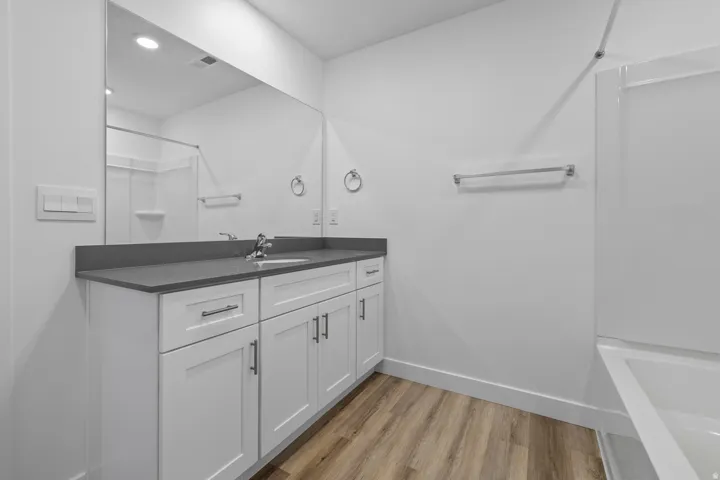 Spacious bathroom featuring a white vanity with a gray countertop, an integrated sink, and an expansive wall-mounted mirror
