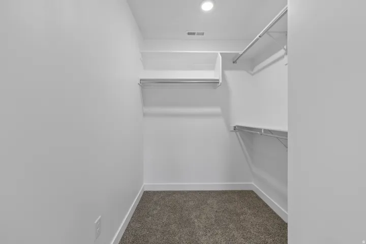 Spacious walk-in closet featuring built-in shelving and hanging rods