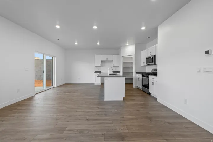 Open-concept living area featuring wood-finish flooring, recessed lighting, and a modern kitchen