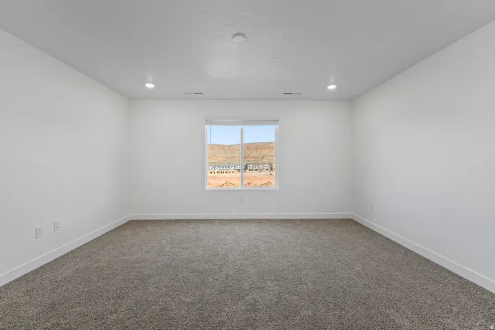 Spacious room featuring neutral carpet, white walls, and a large window