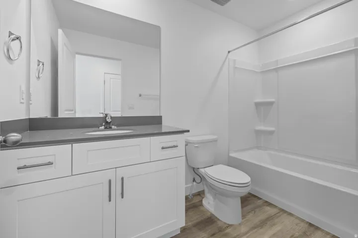 Bathroom featuring a single vanity with white cabinetry, gray countertop, and an undermount sink