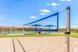 Sand volleyball court featuring a blue net and two blue umbrellas