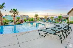 Curved swimming pool with a surrounding concrete deck, lined with multiple lounge chairs