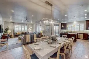 Open-concept living area featuring wood-finish flooring, recessed lighting, and a linear chandelier over the dining space