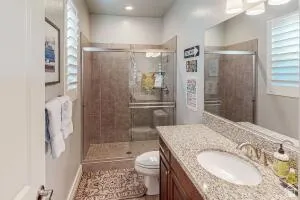 Bathroom featuring a spacious walk-in shower with glass enclosure, a vanity with a light-toned speckled countertop, and a single undermount sink