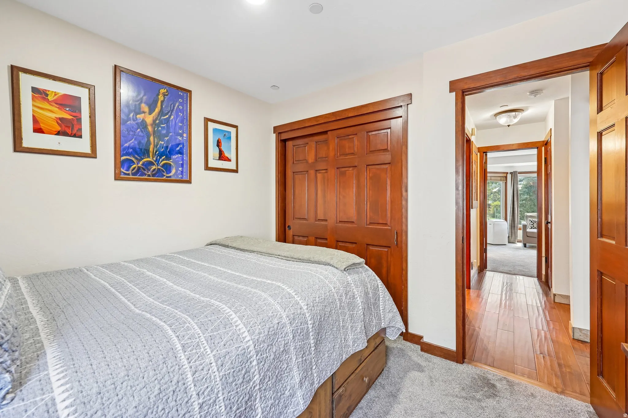 Carpeted sleeping area featuring a paneled wood closet and wood trim