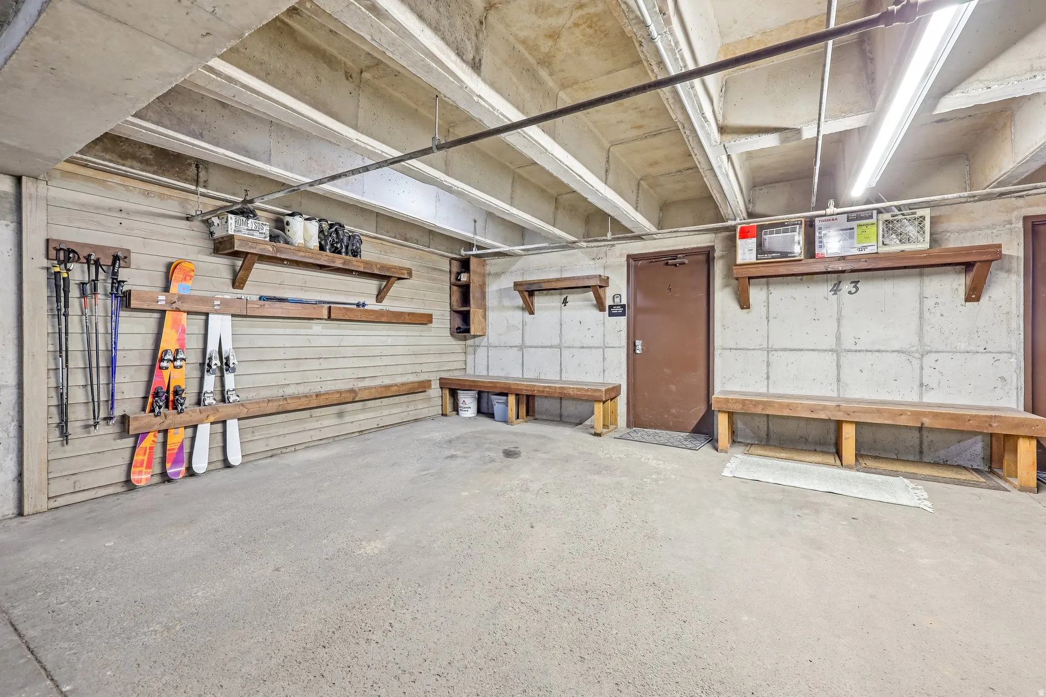 Concrete flooring with exposed ceiling beams and fluorescent lighting