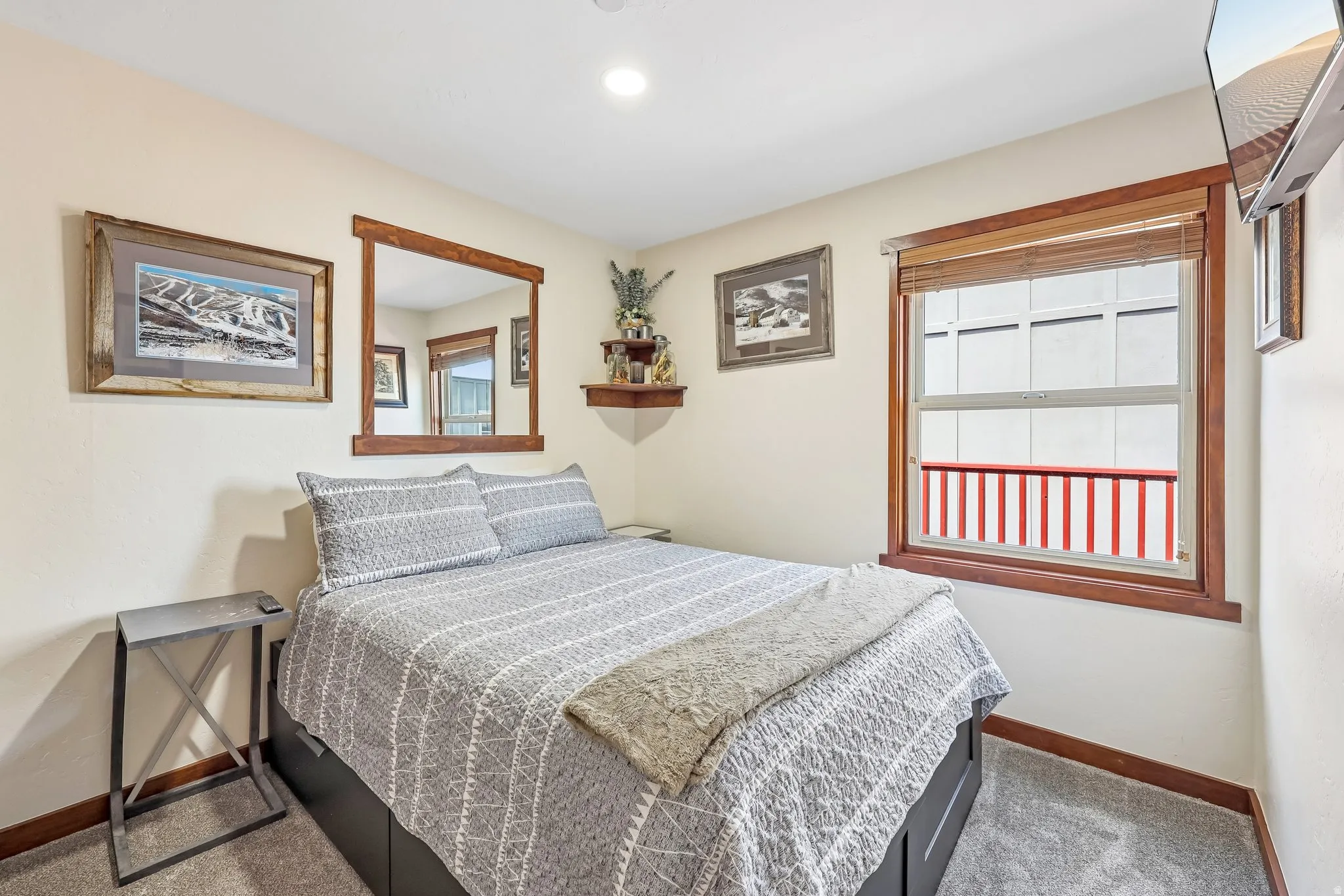 Bedroom featuring neutral wall paint, carpet flooring, a window with wood-finish trim, and a built-in mirror with wood-finish frame