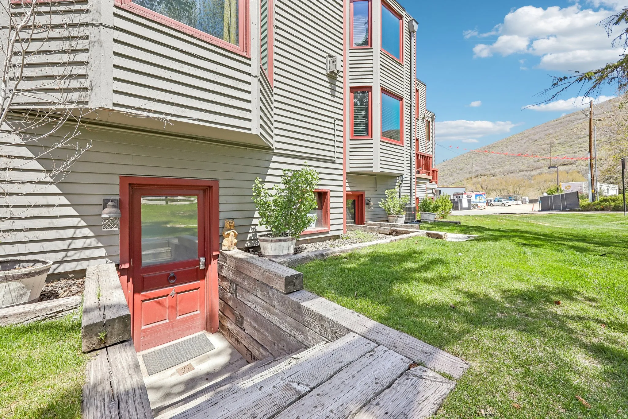 Exterior featuring horizontal siding, red-framed windows, and a red entry door
